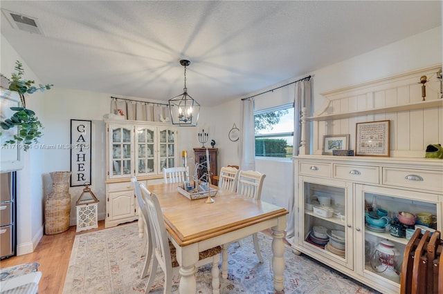 dining area featuring an inviting chandelier, a textured ceiling, and light wood-type flooring