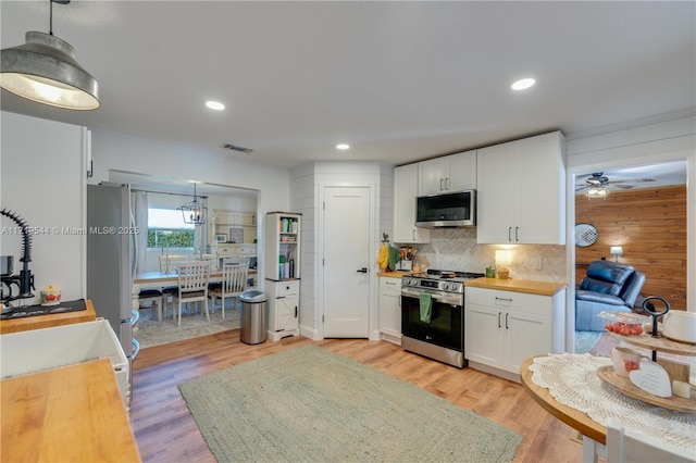 kitchen with wood counters, white cabinetry, hanging light fixtures, ceiling fan, and stainless steel appliances