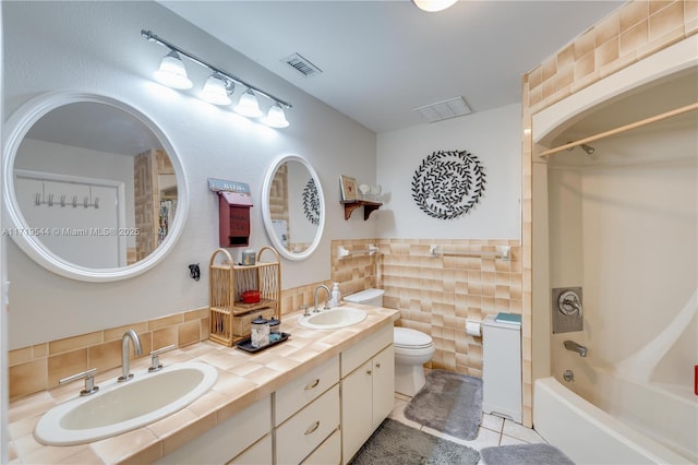 full bathroom featuring tile patterned floors, toilet, tile walls, shower / bath combination, and decorative backsplash