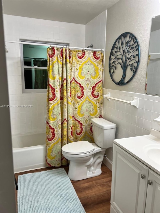 full bathroom featuring tile walls, hardwood / wood-style floors, shower / tub combo, vanity, and toilet