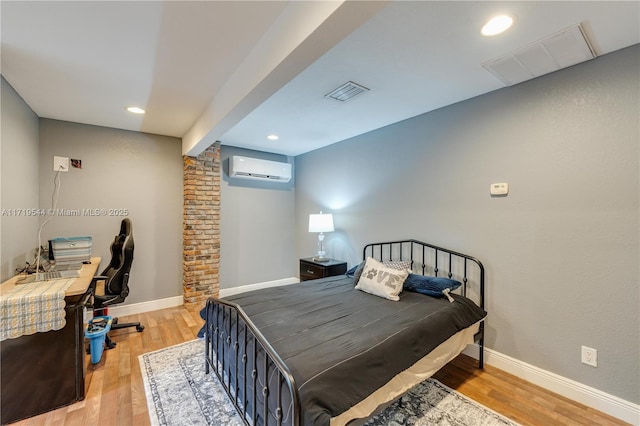 bedroom with light wood-type flooring and an AC wall unit