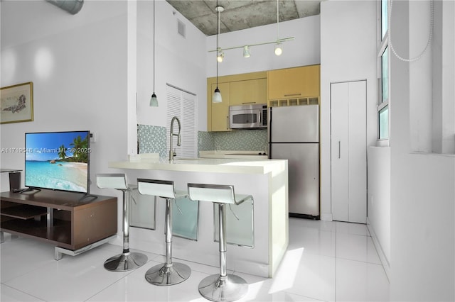 kitchen with visible vents, tasteful backsplash, stainless steel appliances, a peninsula, and light tile patterned flooring