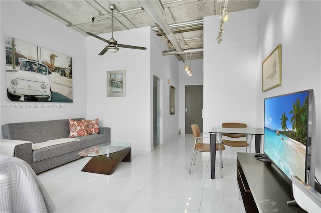 living room featuring baseboards, a high ceiling, and ceiling fan