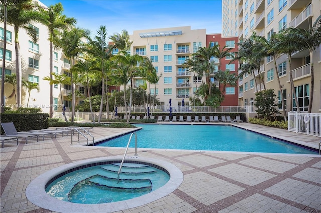 community pool featuring a hot tub, a patio, and fence