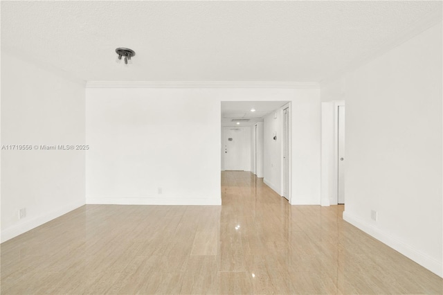 spare room with light hardwood / wood-style floors, ornamental molding, and a textured ceiling