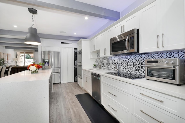 kitchen featuring backsplash, beamed ceiling, white cabinetry, hanging light fixtures, and appliances with stainless steel finishes