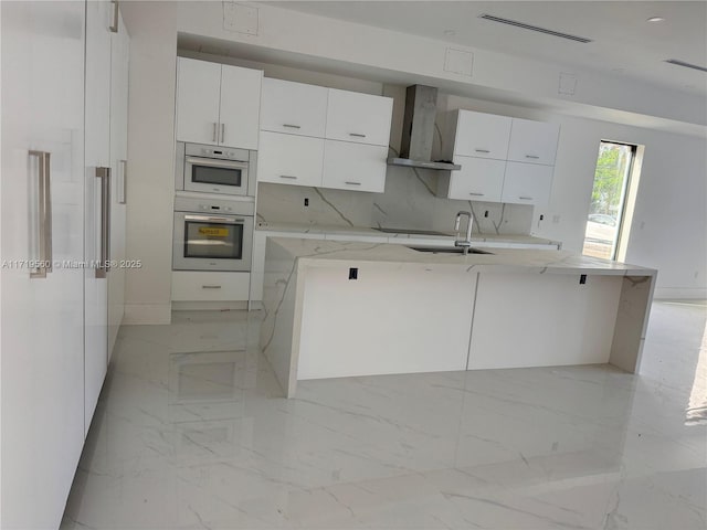 6190 SW 128th St, Pinecrest, FL 33156 - kitchen with wall chimney range hood, modern cabinets, light marble finish floors, white cabinets, and a center island with sink