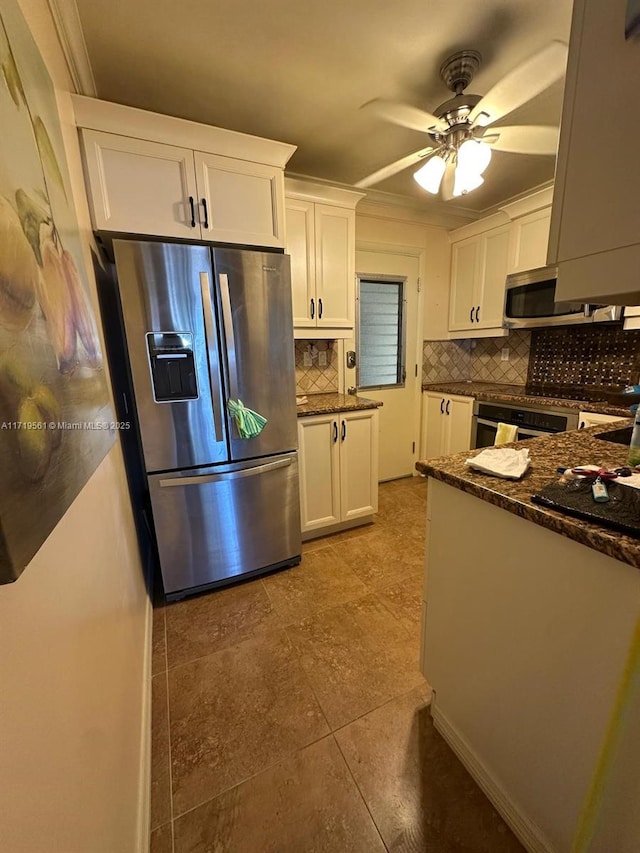 kitchen with appliances with stainless steel finishes, tasteful backsplash, dark stone counters, ceiling fan, and white cabinetry