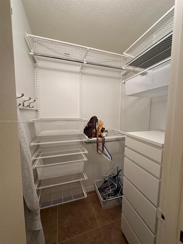 walk in closet featuring dark tile patterned flooring