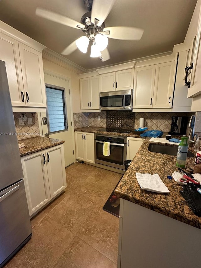 kitchen with ceiling fan, sink, stainless steel appliances, dark stone countertops, and white cabinets