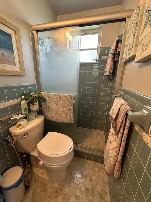 bathroom with toilet, an enclosed shower, and tile walls