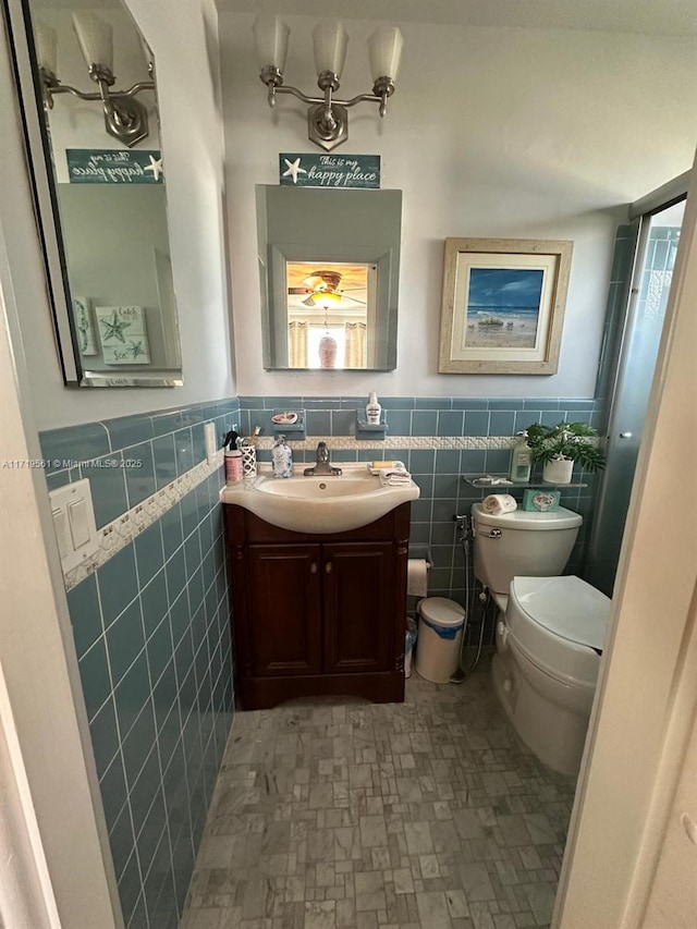 bathroom featuring vanity, tile walls, and toilet