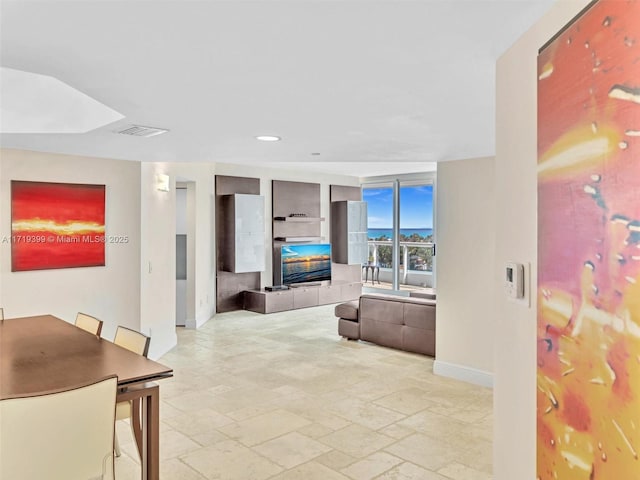 living area featuring stone tile floors, baseboards, visible vents, a fireplace, and recessed lighting