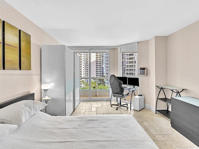 bedroom with baseboards, stone tile flooring, and floor to ceiling windows