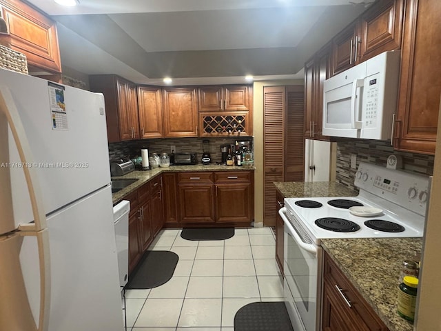 kitchen with decorative backsplash, stone counters, white appliances, and light tile patterned floors