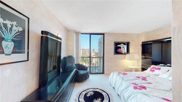 bedroom featuring carpet, a wall of windows, and a textured ceiling