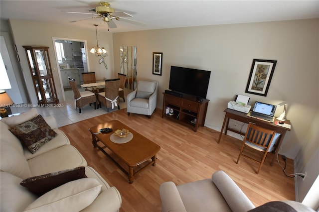 living room with ceiling fan with notable chandelier and light hardwood / wood-style flooring