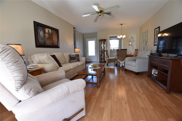 living room with ceiling fan with notable chandelier and light wood-type flooring