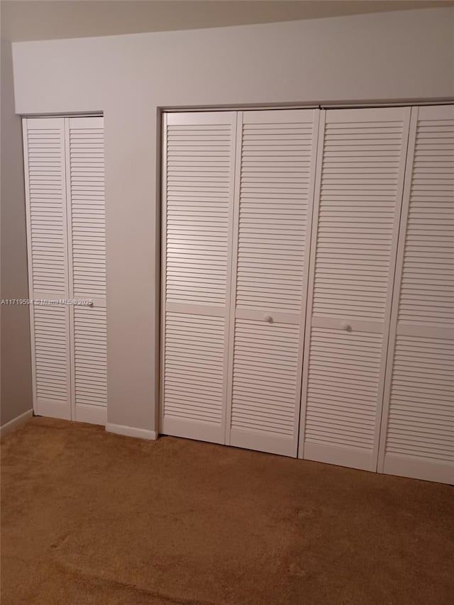 unfurnished bedroom featuring multiple closets and carpet floors