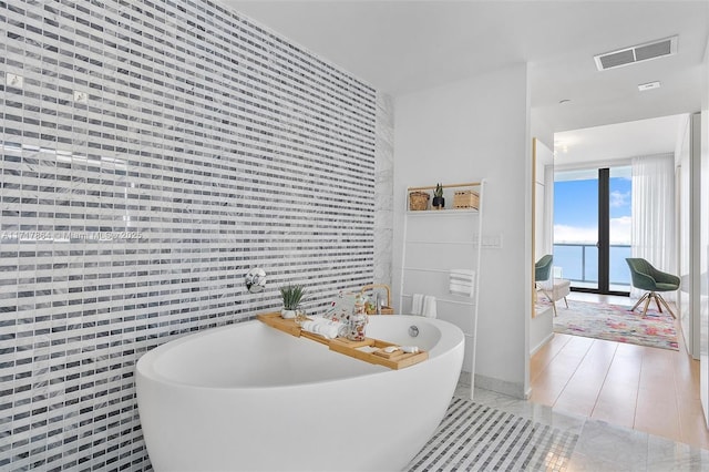 bathroom with a water view, tile walls, and a bath