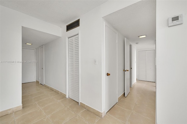 hall featuring light tile patterned floors and a textured ceiling