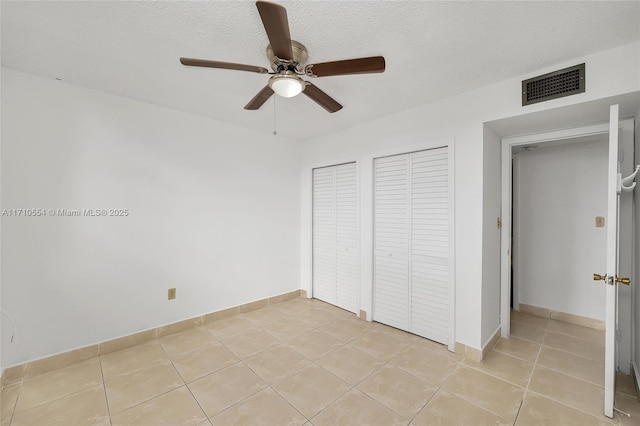 unfurnished bedroom featuring ceiling fan, light tile patterned floors, and a textured ceiling