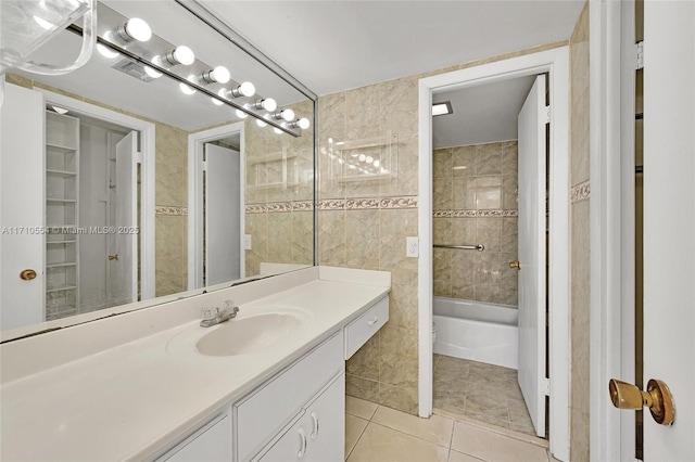 bathroom with tile patterned flooring, vanity, shower / washtub combination, and tile walls