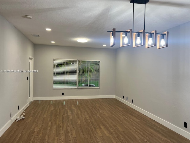 spare room featuring a textured ceiling and dark hardwood / wood-style floors