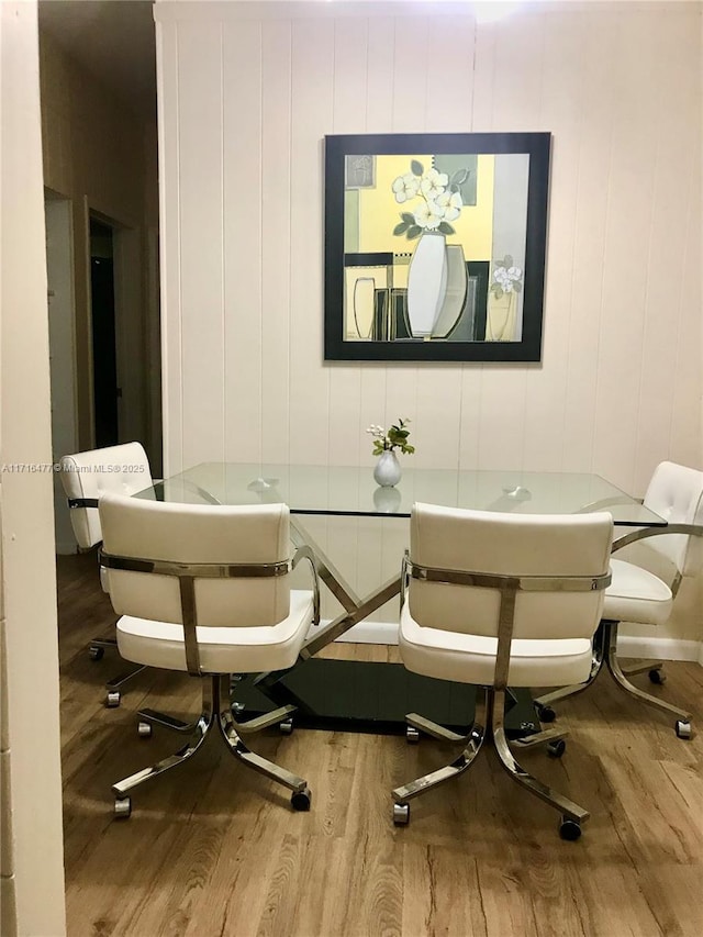 dining space with hardwood / wood-style floors and wood walls