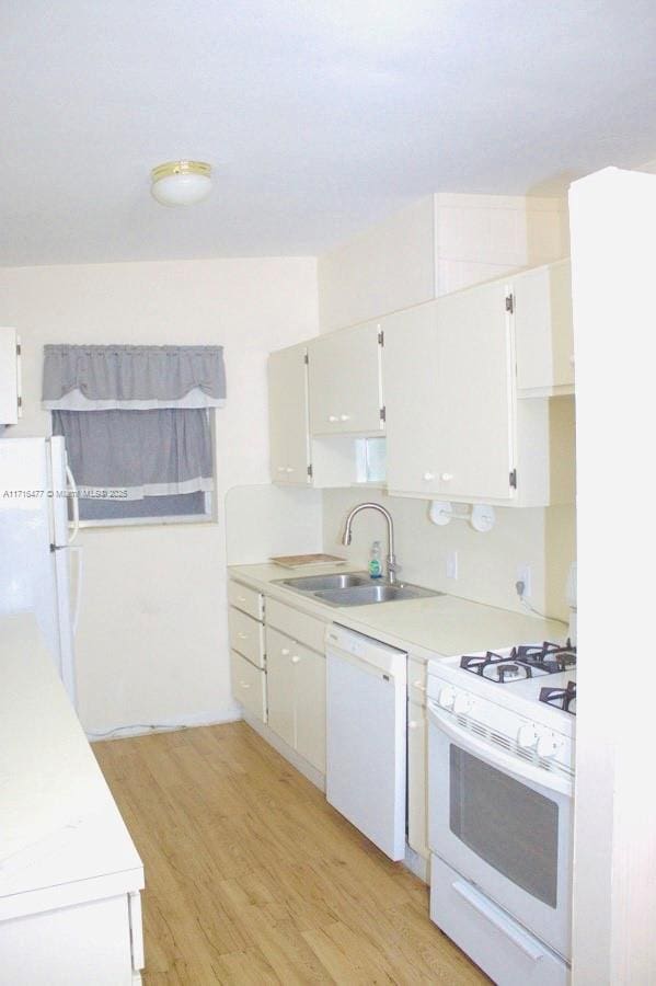 kitchen featuring white appliances, light hardwood / wood-style floors, white cabinetry, and sink