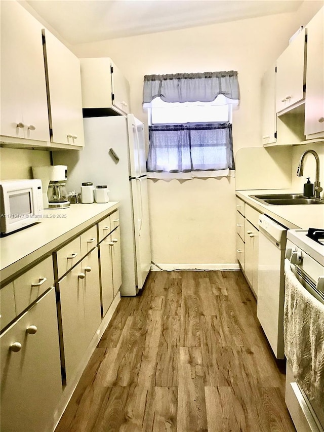 kitchen with sink, white cabinets, dark wood-type flooring, and white appliances