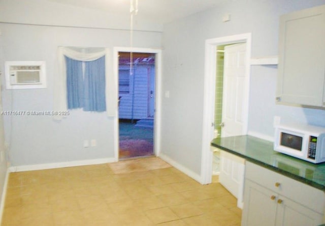 kitchen with a wall mounted AC and white cabinetry