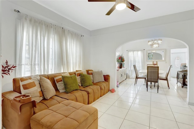 tiled living room featuring ceiling fan with notable chandelier