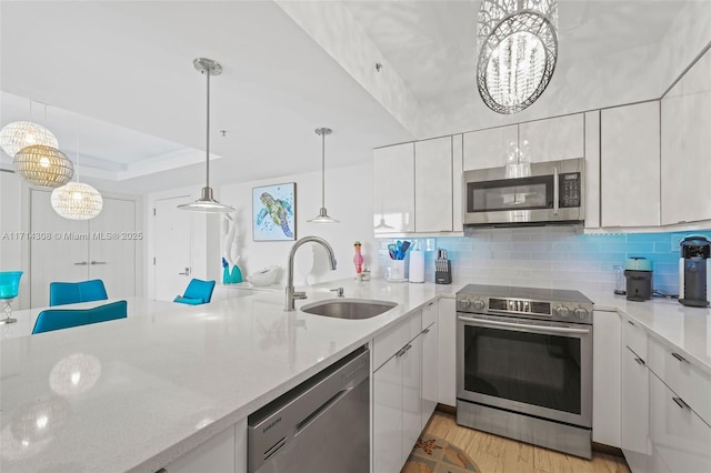 kitchen with stainless steel appliances, sink, decorative light fixtures, a notable chandelier, and white cabinets