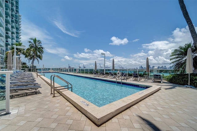 view of pool with a water view and a patio