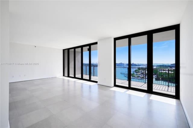 empty room featuring a water view and a wall of windows