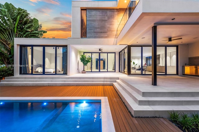 pool at dusk featuring ceiling fan and a jacuzzi