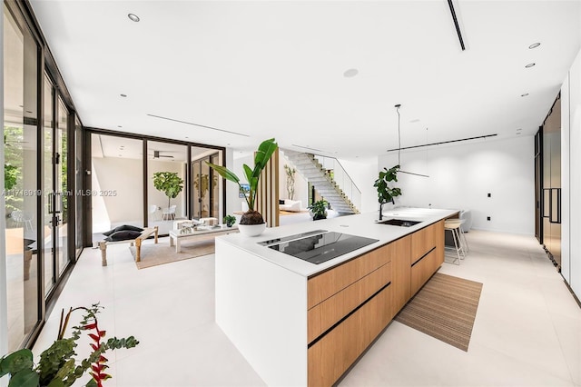 kitchen featuring floor to ceiling windows, sink, a spacious island, decorative light fixtures, and black electric cooktop