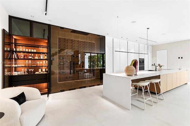 interior space with pendant lighting, sink, a kitchen bar, and an island with sink