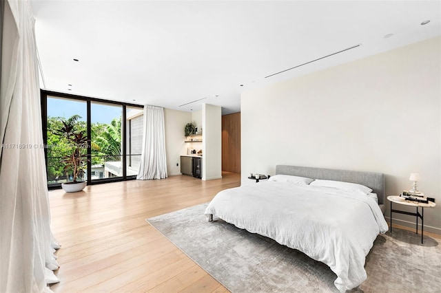 bedroom with access to outside, light hardwood / wood-style flooring, and floor to ceiling windows