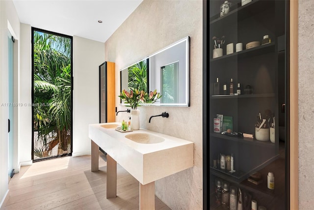 bathroom with hardwood / wood-style floors, expansive windows, and double sink