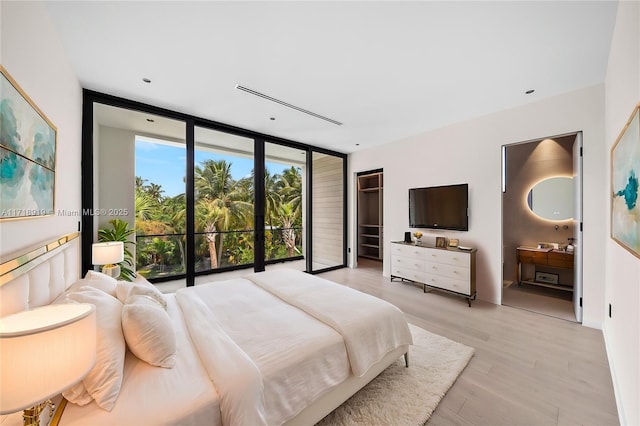 bedroom featuring expansive windows and light hardwood / wood-style floors