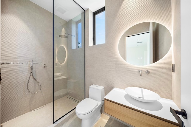 bathroom featuring decorative backsplash, vanity, tiled shower, tile walls, and toilet