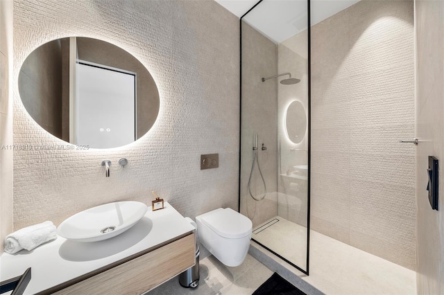 bathroom featuring a tile shower, vanity, tile walls, tile patterned flooring, and toilet