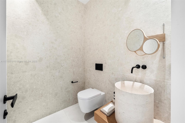 bathroom featuring tile patterned flooring, toilet, and tile walls