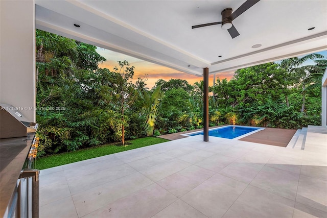 pool at dusk with a patio and ceiling fan