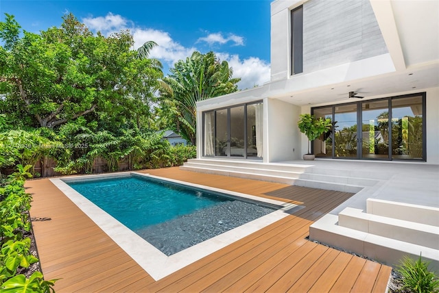 view of swimming pool with ceiling fan and a deck