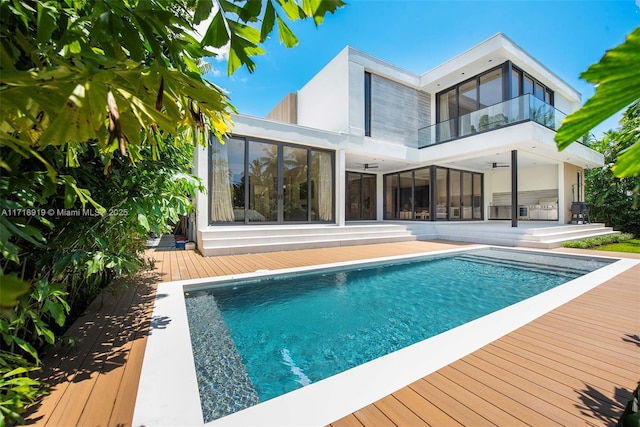 rear view of house featuring a swimming pool side deck, a balcony, and ceiling fan