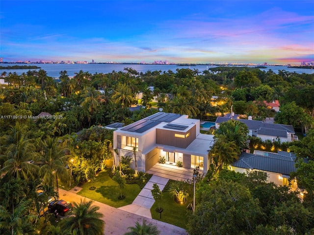 aerial view at dusk featuring a water view