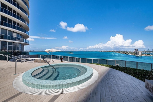 view of pool featuring a water view and a hot tub